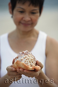 Asia Images Group - Woman at the beach holding a sea shell