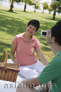 Asia Images Group - Mature couple having a picnic in the park and taking a picture