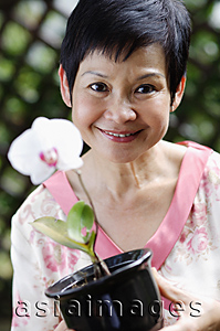 Asia Images Group - Woman with flower smiling at camera