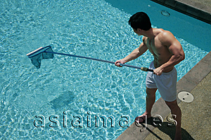 Asia Images Group - Young man cleaning swimming pool