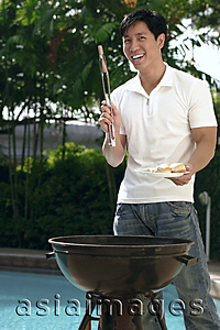 Asia Images Group - Young man having a barbeque