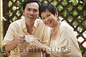 Asia Images Group - Mature couple smiling at camera while having tea