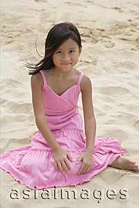 Asia Images Group - Young girl sitting in the sand and smiling at camera