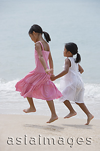 Asia Images Group - Sisters running on the beach and holding hands