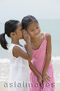 Asia Images Group - Girl whispering into sister's ear