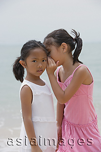 Asia Images Group - Girl whispering into sister's ear