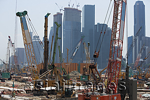 Asia Images Group - Cranes at construction site in front of cityscape