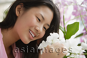 Asia Images Group - Young woman smiling at flower