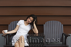 Asia Images Group - Young woman enjoying cup of tea in garden chair