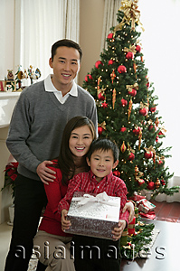 Asia Images Group - Young parents with boy present in hand at Christmas smiling at camera