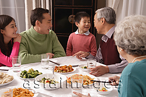 Asia Images Group - Family chatting over at dinner table having traditional food