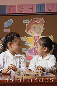 Asia Images Group - Schoolgirls in class playing with blocks looking at each other