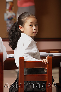 Asia Images Group - Schoolgirl in class turning head around looking at camera
