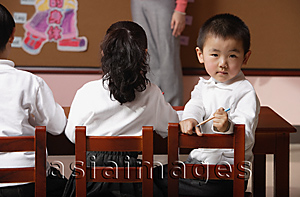 Asia Images Group - Students in class with teacher, schoolboy turning head around looking at camera