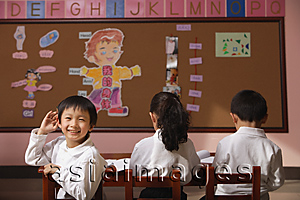 Asia Images Group - Students in class, schoolboy turning head around looking at camera