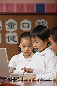 Asia Images Group - Young students using laptop in class, schoolboy typing on keypad