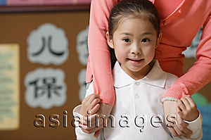Asia Images Group - Young schoolgirl smiling at camera with teacher