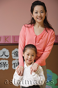 Asia Images Group - Young schoolgirl with teacher, smiling at camera