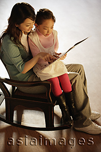 Asia Images Group - Mother and daughter on rocking chair reading a book