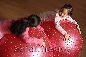 Asia Images Group - Two girls leaning on balls, looking at each other