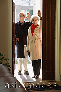 Asia Images Group - Elderly couple in door frame waving at camera