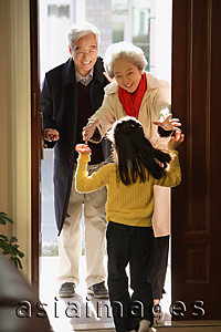 Asia Images Group - Girl greeting grandparents at door