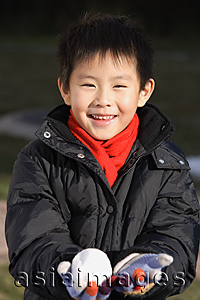 Asia Images Group - Young boy with snowball smiling at camera
