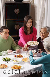 Asia Images Group - Family at dinner table having traditional food
