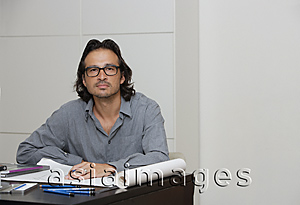 Asia Images Group - Man sitting at desk with pencil and paper, looking at camera