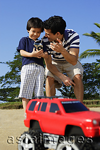 Asia Images Group - Father and son at the beach with remote controlled toy