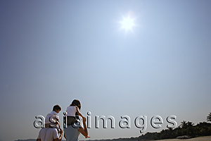 Asia Images Group - Young couple piggybacking children at the beach
