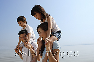 Asia Images Group - Young couple piggybacking children at the beach