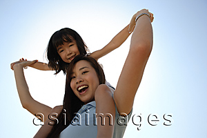 Asia Images Group - Mother piggybacking daughter smiling at the camera