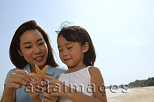 Asia Images Group - Mother and daughter at the beach, looking at shell