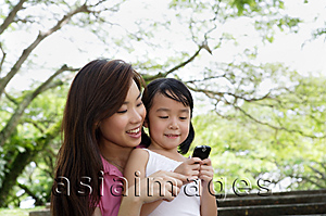 Asia Images Group - Mother and daughter at the park looking at cellphone