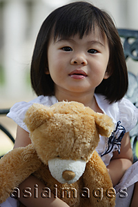 Asia Images Group - A young girl looking at camera, holding teddy bear