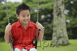AsiaPix - Boy in red shirt sitting on swing, smiling
