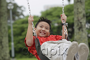AsiaPix - Boy on playground swing, smiling, looking away