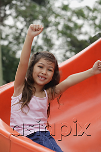 AsiaPix - Girl coming down playground slide, arms outstretched