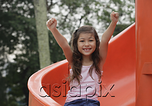 AsiaPix - Girl coming down playground slide, arms outstretched, smiling at camera