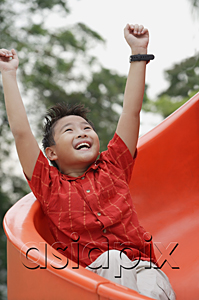 AsiaPix - Boy coming down playground slide, arms outstretched, smiling, looking up