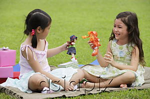 AsiaPix - Two girls sitting on picnic blanket, playing with dolls