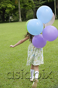 AsiaPix - Girl walking on grass, holding balloons, rear view