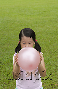 AsiaPix - Girl standing on grass, blowing up pink balloon