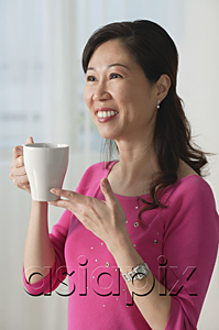 AsiaPix - Mature woman holding cup, smiling, looking away
