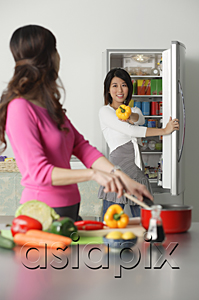 AsiaPix - Mother and adult daughter in kitchen, daughter at refrigerator, holding bell pepper