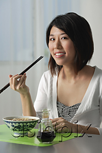 AsiaPix - Young woman with chopsticks, eating a bowl of noodles