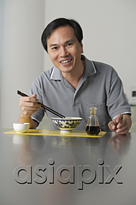 AsiaPix - Mature man sitting and eating a bowl of noodles