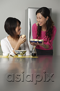 AsiaPix - Mother and daughter in kitchen, older woman offering daughter a plate of Chinese buns