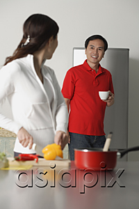 AsiaPix - Mature woman in kitchen preparing a meal, turning to look man standing behind her